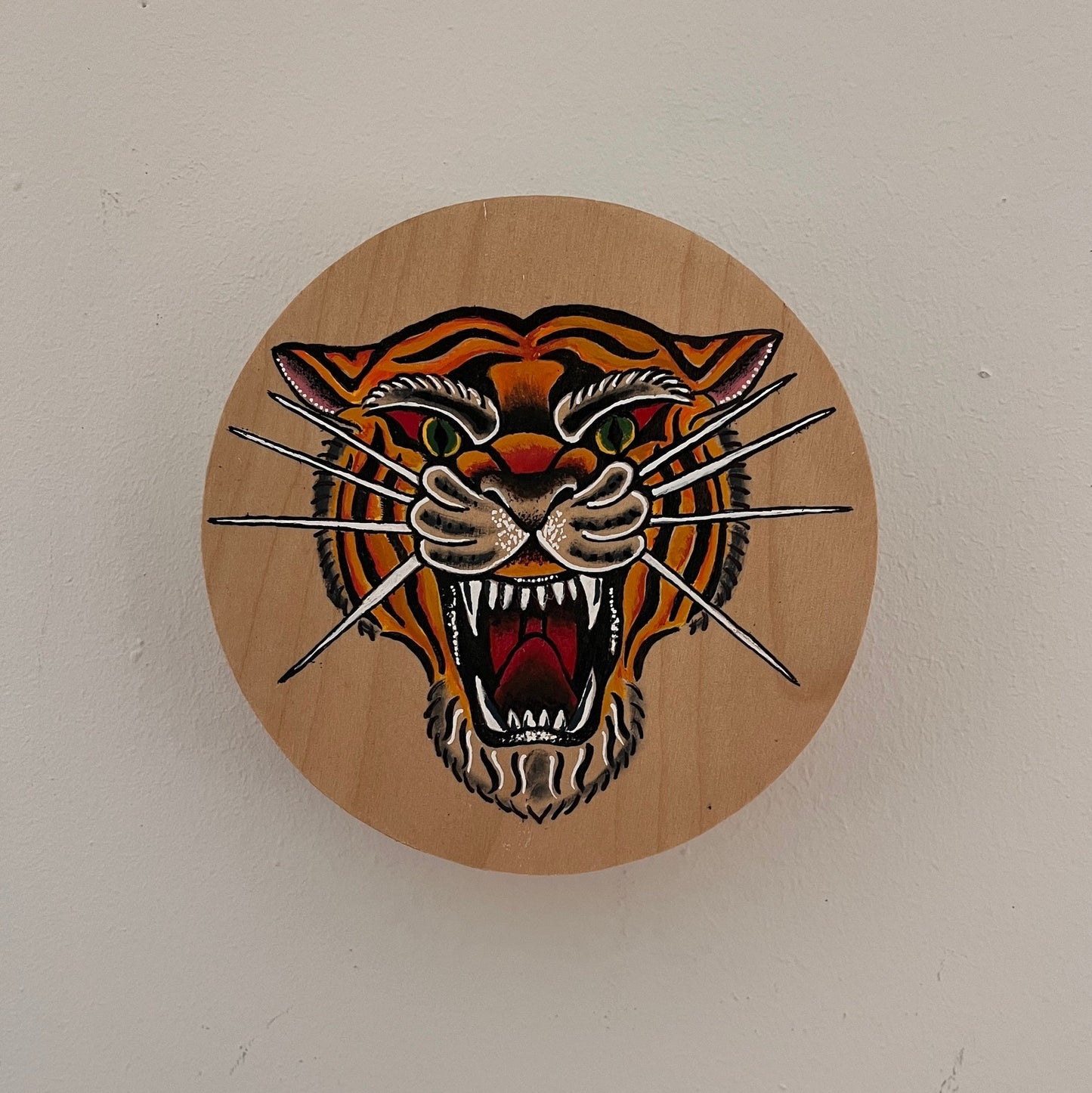Wooden plaque with a tiger design on a white wall