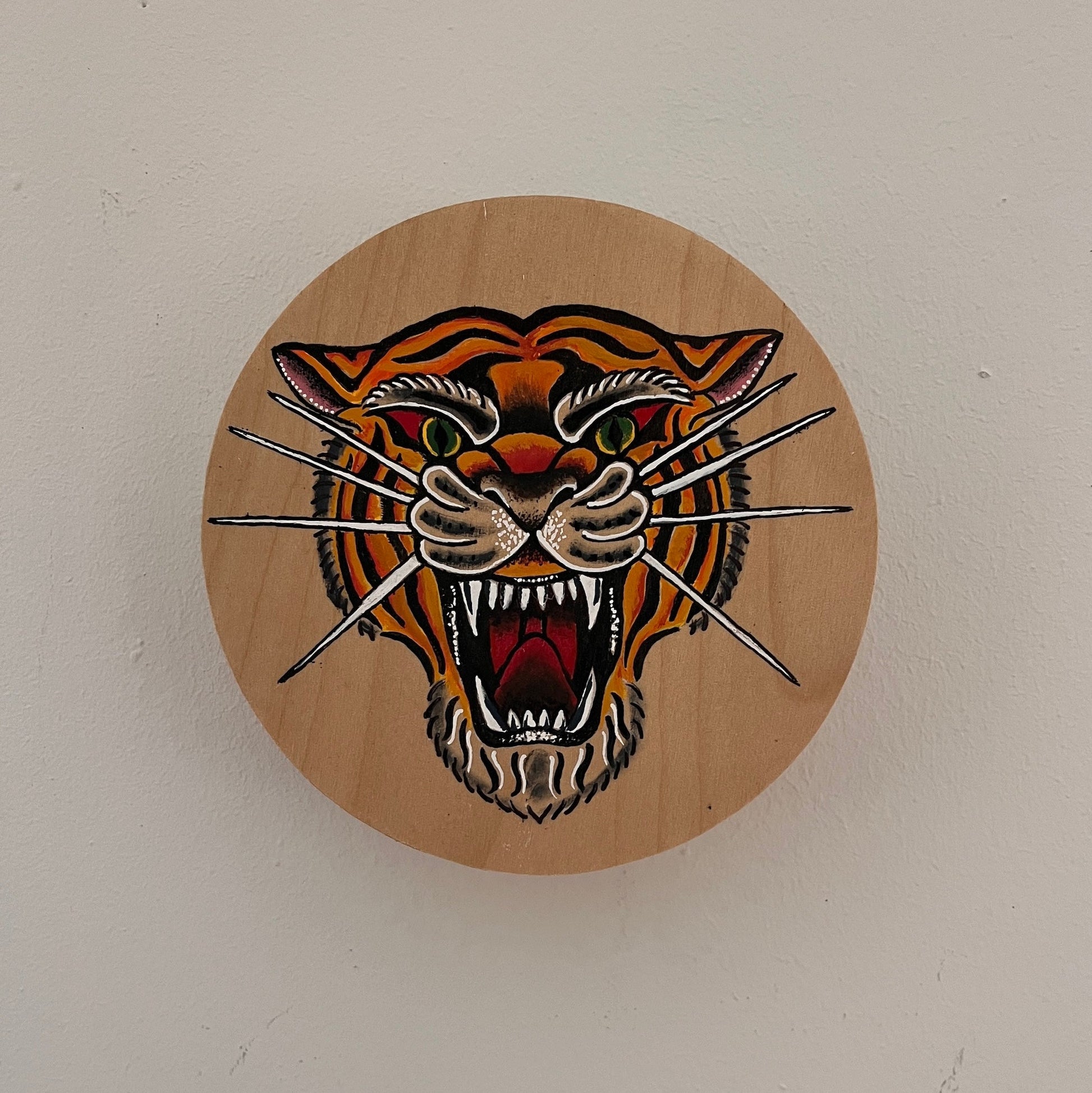 Wooden plaque with a tiger design on a white wall